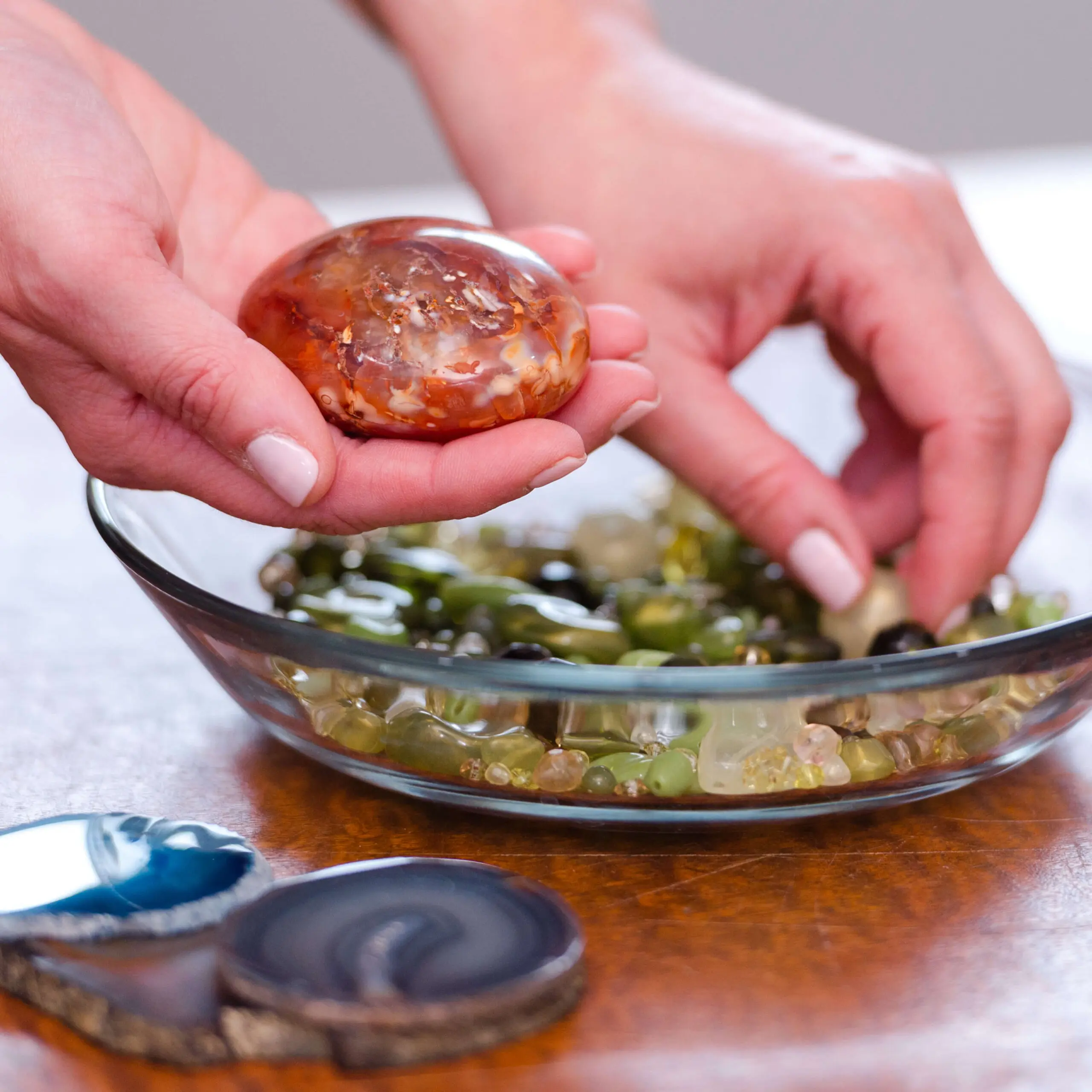 Hands holding an amber-coloured glass stone
